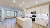 Located at 190 Moll Dr in Santa Rosa Beach, FL, this well-appointed single-floor residence offers 2 bedrooms and 3 bathrooms with a clean, contemporary design throughout. The open-concept kitchen and living area serves as the heart of the home, anchored by a large center island with a undermount sink and white quartz countertops. Crisp white shaker cabinetry extends to the ceiling, complemented by a classic subway tile backsplash and a full suite of stainless steel appliances. Light wood-tone flooring flows seamlessly through the living areas, enhancing the bright, airy atmosphere created by recessed lighting and ceiling fans. The primary bedroom is generously sized and features dual windows that invite natural light, a ceiling fan, and direct access to a private outdoor balcony. Its en-suite bathroom is finished in all-white tile and cabinetry, featuring a glass-enclosed walk-in shower, an extended vanity with an illuminated mirror, and a spacious walk-in closet with built-in wire shelving. The second bedroom is equally well-lit with its own windows and ceiling fan. Additional bathrooms maintain the same refined, all-white aesthetic with modern vanities and LED-backlit mirrors. The residence offers two closets in total, providing ample storage throughout.
