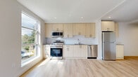 Located at 650 Fairway Ave in Langford, BC, this thoughtfully designed one-bedroom, one-bathroom unit offers a clean, modern aesthetic throughout its efficiently organized single-floor layout. The open-concept living, dining, and kitchen area serves as the heart of the space, anchored by large windows that flood the room with natural light and offer pleasant outdoor views of the surrounding neighbourhood. Light hardwood-style flooring runs throughout, complementing the bright, white walls and creating a warm, airy atmosphere.

The kitchen is well-appointed with light wood cabinetry extending to the upper and lower walls, a full suite of stainless steel appliances including a range, built-in microwave, dishwasher, and refrigerator, as well as grey countertops and a clean tile backsplash. A private balcony extends the living area outdoors, ideal for taking in the natural surroundings.

The bedroom is a calm, sun-filled retreat with light-toned flooring and ample wall space. Two closets provide generous storage. The bathroom features a full soaker tub and shower combination with crisp white surround, warm wood vanity cabinetry, grey countertop, and black hardware accents. A dedicated laundry area and hallway complete the functional layout of this well-designed Langford home.