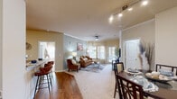 Located in Ooltewah, Tennessee, this well-appointed 2-bedroom, 2-bathroom single-floor residence offers a thoughtfully designed layout with a warm and welcoming ambiance throughout. The combined living and dining area serves as the heart of the home, featuring warm-toned carpet, hardwood-style flooring at the entry, crown molding, and a ceiling fan. Large windows allow generous natural light to fill the living room, while a sliding door provides additional brightness and outdoor access. The dining area accommodates a full-sized table and benefits from track lighting overhead. A built-in desk nook near the entry adds functional workspace. The kitchen is equipped with rich dark wood cabinetry, light countertops, black appliances including a refrigerator, range, and microwave, and hardwood-style flooring. The spacious primary bedroom features dual windows, a ceiling fan, plush carpet, and ample closet space. The second bedroom is equally comfortable, also outfitted with a ceiling fan and carpet. The two bathrooms include one with a walk-in glass-door shower and hardwood-style flooring, and another with a tub-shower combination, a wide vanity mirror, and wood cabinetry. A hallway and two closets round out the functional floor plan.