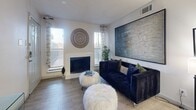 Located in Dallas, TX, this well-appointed one-bedroom, one-bathroom unit offers a thoughtfully designed layout across a single floor. The entryway welcomes you with light wood-style flooring and neutral tones that carry throughout the space, creating a clean and cohesive aesthetic.

The combined kitchen and living area serves as the heart of the unit. The living room features a white fireplace flanked by two windows that allow natural light to fill the room, complemented by light-filtering curtains. The kitchen is outfitted with white cabinetry, stainless steel appliances including a microwave and range, a black refrigerator, and a light-colored countertop peninsula that doubles as a breakfast bar, providing both functionality and a natural separation between the kitchen and living spaces.

The bedroom is a comfortable retreat with a ceiling fan, access to a private balcony through sliding glass doors with vertical blinds, and enough space for a full bedroom suite. A dedicated closet provides ample storage.

The bathroom includes a tub-shower combination, a white vanity with sink, and wood-style flooring that ties in with the rest of the unit. Throughout the space, textured ceilings and consistent light-toned walls contribute to a bright, airy atmosphere well-suited for comfortable everyday living.