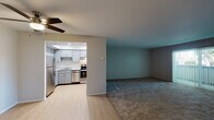 Located at 1120 W Olive Ave in Sunnyvale, California, this single-floor residence offers a practical and well-organized layout designed for comfortable everyday living. The open-concept living and kitchen area forms the heart of the home, where light wood-look flooring in the kitchen transitions seamlessly into carpeted living space. A ceiling fan overhead provides year-round comfort in the living area, which is bathed in a cool teal accent color that adds a modern touch to the neutral palette throughout.

The kitchen is thoughtfully equipped with grey shaker-style cabinetry, quartz countertops, stainless steel appliances including a refrigerator, range, and dishwasher, and a double-basin stainless steel sink. A skylight above the kitchen enhances natural illumination, creating a bright and functional workspace. Ample upper and lower cabinet storage ensures generous organization options.

The bedrooms are carpeted and generously sized, each featuring ceiling fans and vertical blinds over windows that allow for natural light and outdoor views. A closet with a hanging rod provides practical storage. The hallway connects the rooms efficiently and includes a vanity area with grey cabinetry and quartz countertops, consistent with the home's cohesive design aesthetic. Light wood-look flooring extends through the hallway, reinforcing the clean, modern feel of this Sunnyvale residence.