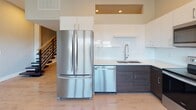 Located at 1685 Elmwood Ave in Buffalo, NY, this two-story space offers a thoughtfully designed interior with modern finishes throughout. Light-toned luxury vinyl plank flooring runs consistently across both levels, contributing to a clean, cohesive aesthetic.

The kitchen is outfitted with a full suite of stainless steel appliances, including a French door refrigerator, dishwasher, electric range, and over-the-range microwave. Cabinetry features a two-tone design pairing white upper cabinets with dark lower cabinets, complemented by light quartz countertops and a white subway tile backsplash. A staircase with modern metal railing connects the two floors.

Open living areas on both levels provide flexible use of space. Upper-level rooms feature rows of horizontal clerestory windows along the upper portion of the walls, allowing natural light to fill the rooms while the whitewashed plank ceilings add texture and warmth. Lower-level living spaces benefit from larger windows fitted with roller shades, offering views of the surrounding neighborhood.

Two bathrooms serve the space. One features stone-look tile flooring, a dark wood vanity, and a glass-enclosed shower with large-format tile. The second bathroom offers a clean, minimalist design with a walk-in glass shower, white tile surround, chrome fixtures, and neutral floor tile throughout.