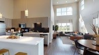 This contemporary two-story residence makes a striking first impression with its dramatic double-height ceilings in the open-concept main living area. The kitchen is a standout, featuring light wood-grain cabinetry extending to lofted heights, a dark subway tile backsplash, stainless steel appliances, and a large white quartz island that flows seamlessly into the dining and living spaces. Hardwood-style flooring runs throughout the main level, anchoring the bright, airy atmosphere created by expansive windows that frame sweeping views of open meadows and tree canopies beyond.

The living room benefits from abundant natural light, with oversized windows and sheer drapery enhancing the connection to the outdoors. The primary bedroom suite includes a generous walk-in closet with built-in organizers and an en-suite bathroom with dual sinks, a wide quartz vanity, and wood-grain cabinetry. An additional bedroom offers plush carpet flooring, a bold accent wall, and natural views through large windows. A second full bathroom features dark tile surround in the tub/shower combination and matching cabinetry finishes.

The upper level provides a versatile loft-style bonus room with carpet, a closet, and a built-in desk area—ideal as a home office or lounge. Throughout, the design balances modern finishes with a warm, livable aesthetic.