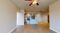 This single-floor residence offers a thoughtfully designed open-concept layout that seamlessly connects the kitchen, dining, and living areas. The kitchen is a standout feature, showcasing contemporary light wood cabinetry, a full suite of stainless steel appliances including a refrigerator, range, and microwave, and a large central island with a clean white countertop that provides generous prep and serving space. Pendant lighting and track lighting add a modern touch overhead, while light wood-look flooring unifies the main living area.

The living space is bright and airy, benefiting from multiple windows that invite natural light and outdoor views. A ceiling fan adds comfort and a sense of openness to the room. Built-in shelving offers additional storage and display options along one wall.

The bedrooms are carpeted for warmth and comfort, each featuring ceiling fans with light fixtures and multiple windows dressed with white blinds, allowing for both natural light and privacy. The bathrooms are finished with tile flooring, dark wood vanity cabinetry, granite-style countertops, and a shower-tub combination, complemented by well-lit vanity mirrors. Closet storage is conveniently accessible from the bathroom area. The overall palette of neutral tones and clean lines creates a fresh, move-in-ready atmosphere throughout.