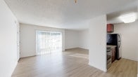 This single-floor residence offers a well-organized layout that balances open living spaces with private sleeping quarters. The main living and dining area is a standout, featuring light-toned luxury vinyl plank flooring, crisp white walls, and a textured ceiling that adds character. A large sliding glass door fitted with vertical blinds floods the space with natural light and provides outdoor access, creating an airy, welcoming atmosphere throughout.

Adjacent to the living area, the kitchen is equipped with rich, warm-toned wood cabinetry, granite-look countertops, a stainless steel single-basin sink, and modern brushed nickel hardware. A pass-through opening connects the kitchen to the main living space, enhancing the open feel of the layout. Stainless steel appliances complete the functional kitchen setup.

The bedrooms are carpeted for comfort and feature ample closet space with built-in rods and shelving. Each room is finished with the same neutral white walls and textured ceilings, maintaining a clean, consistent aesthetic. Natural light enters through windows dressed with vertical blinds, and baseboard heating ensures year-round comfort.

The bathroom is neatly appointed with a tub-shower combination, brushed nickel fixtures, and clean white finishes throughout. The overall design of this residence is straightforward and functional, offering a well-maintained, move-in-ready environment.