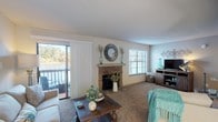 Located at 133 Lake Front Dr in Daphne, Alabama, this single-floor residence offers a well-designed layout with comfortable living spaces and notable architectural details throughout. The spacious living room serves as the heart of the home, anchored by a striking stone fireplace with a classic mantel and accented by sliding glass doors that open to a balcony overlooking the water — a standout feature that fills the room with natural light and scenic views. Plush carpeting and large windows enhance the warm, inviting atmosphere. Adjacent to the living room, a dedicated dining area provides a bright, windowed space ideal for everyday meals or entertaining. The kitchen is outfitted with light-toned cabinetry, granite-style countertops, and stainless steel appliances including a range, microwave, and refrigerator, all set atop wood-look flooring. The bedrooms are generously sized, each featuring carpet flooring, ceiling fans, and windows dressed with blinds and sheer curtains that invite soft, natural light. The bathrooms are well-appointed with updated vanities featuring stone-look countertops, ample under-sink storage, and shower-tub combinations. Overall, the home presents a cohesive, comfortable living environment in a desirable lakefront setting.