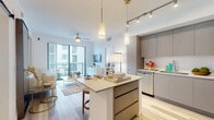 Located at 445 Hialeah Dr in Hialeah, Florida, this single-floor residence showcases a sleek, contemporary design with light wood-style flooring and a bright, neutral color palette throughout. The open-concept living and kitchen area serves as the heart of the home, where a well-appointed kitchen features flat-front gray cabinetry extending to the ceiling, stainless steel appliances including a refrigerator, range, microwave, and dishwasher, and a generous center island with quartz countertops and bar seating. Pendant lighting and track lighting illuminate the space, complementing the natural light that pours in through floor-to-ceiling sliding glass doors that lead to a private balcony. A ceiling fan in the living area adds both comfort and style. The bedrooms are tranquil retreats with light-toned flooring, ceiling fans, and ample natural light from large windows. Each bedroom is accompanied by a dedicated walk-in closet with built-in shelving. The bathrooms are finished with clean-lined vanities, quartz countertops, undermount sinks, and wood-framed mirrors. A sliding barn door detail adds a modern architectural touch. The overall ambiance is bright, airy, and refined, reflecting a thoughtfully designed contemporary living space.
