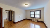 Located at 3433 Clifton Ave in Cincinnati's Clifton neighborhood, this single-floor unit showcases classic architectural character throughout. Warm hardwood floors extend across the main living areas and bedrooms, complemented by rich, dark wood trim, baseboards, and door frames that lend a timeless, cohesive aesthetic.

The living spaces are bright and open, with windows fitted with blinds allowing natural light to filter in. Charming arched doorways connect the rooms, adding an elegant architectural detail consistent with the building's traditional style. Radiator heating units are present in multiple rooms, reflecting the building's classic construction.

The kitchen is well-equipped with dark wood cabinetry, granite-style countertops, a gas range, double-basin sink, and a dishwasher. Tile flooring in the kitchen provides a practical contrast to the hardwood found throughout the rest of the unit.

The bedrooms are generously sized, each featuring hardwood floors and ample closet space, including built-in shelved closets and wardrobe-style closets with dark wood doors. Crown molding details add a refined touch in select rooms.

Hallways connect the spaces seamlessly, with doorways framed in the same rich dark wood trim found throughout, creating a unified and well-maintained interior. The overall ambiance is warm, classic, and functional, suited for comfortable everyday living.