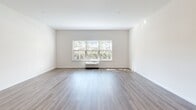 Located at 293 East Main Street in Patchogue, NY, this well-appointed two-bedroom, two-bathroom unit offers a thoughtfully designed single-floor layout with generous living space. The open-concept kitchen and living area serves as the heart of the home, featuring warm hardwood-style flooring, crisp white walls, and abundant natural light. The kitchen is outfitted with white shaker cabinetry, a subway tile backsplash, stainless steel appliances including a range, microwave, and refrigerator, and a peninsula with pendant lighting overhead — ideal for both cooking and casual dining.

The living area is bright and expansive, highlighted by a large multi-pane window that frames outdoor greenery and fills the space with natural light. Both bedrooms are carpeted for comfort and include windows with outdoor views, providing a peaceful retreat. The spacious primary bedroom is complemented by a dedicated closet with built-in wire shelving for organized storage.

Both bathrooms are identically styled with classic white subway tile tub surrounds, patterned mosaic penny tile flooring, white vanities with undermount sinks, and pendant lighting — combining timeless design with modern functionality. The overall aesthetic throughout is clean, contemporary, and move-in ready.