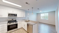 Located at 4009 Enterprise Rd in Bowie, MD, this well-appointed 2-bedroom, 2-bathroom residence offers a thoughtfully designed single-level layout. The open-concept kitchen and living area serves as the heart of the home, featuring crisp white shaker cabinetry, granite countertops, and a full suite of stainless steel appliances including a refrigerator, electric range, built-in microwave, and dishwasher. A peninsula with pendant lighting provides additional prep space and creates a seamless connection to the living area. Light wood-style flooring runs throughout the entire residence, lending a clean and cohesive aesthetic. Both bedrooms are bright and comfortable, each benefiting from natural light through windows with views of surrounding greenery. The primary bedroom includes generous closet space, and the unit as a whole features an impressive seven closets, ensuring exceptional storage throughout. Both bathrooms are finished in a clean, modern style with subway tile tub/shower surrounds, granite-topped vanities, and wood-style flooring. The overall design palette of neutral tones and white finishes creates a bright, airy ambiance that is both functional and contemporary.