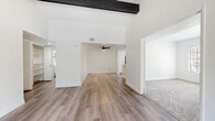Located in the desirable coastal community of Encinitas, California, this two-story home at 1320 Via Terrassa offers a thoughtfully updated interior with a clean, modern aesthetic throughout. The main living area is bright and open, showcasing wide-plank wood-style flooring, crisp white walls, and a decorative dark wood beam accent overhead. A ceiling fan and elevated ceiling height add to the airy feel of the space, which flows seamlessly toward the kitchen and adjacent carpeted rooms.

The kitchen is well-appointed with white shaker-style cabinetry, matte black hardware, light quartz countertops, stainless steel appliances, and a window that brings in natural light above the sink. The layout is functional and efficient, with a peninsula providing additional workspace and defining the kitchen from the living area.

Bedrooms feature plush neutral carpeting and large windows that frame views of the surrounding greenery, creating a calm and restful atmosphere. Sliding glass doors in one room open directly to an outdoor balcony, offering a private connection to the lush, tree-lined exterior.

The bathrooms are finished with white vanities, quartz countertops, and matte black fixtures, giving them a contemporary, cohesive look. The exterior dollhouse view reveals a well-positioned structure surrounded by mature trees and landscaping, further enhancing the home's tranquil setting.