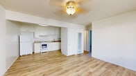 Located at 505 W Madison Ave in El Cajon, CA, this single-floor, 2-bedroom, 1-bathroom unit offers a practical and well-organized layout. The living room greets you at the entry with light wood-style laminate flooring, a ceiling fan, a wall-mounted HVAC unit, and a front-facing window that draws in natural light. A security screen door at the entrance adds an extra layer of safety while allowing fresh air to flow through.

The kitchen is efficiently designed with white cabinetry extending to the upper walls, a gas range, refrigerator, and a single-basin sink with a under-cabinet range hood. Laminate countertops and additional lower cabinet storage complete the functional space, which shares the same wood-style flooring as the living area.

Both bedrooms feature neutral carpet, bright white walls, and windows with views of the outdoors. The primary bedroom includes a closet with a rod and shelf system, providing practical storage. The second bedroom is equally bright and well-proportioned.

The bathroom is clean and straightforward, featuring a tiled shower-tub combination with white square tile surround and a curtain rod. The unit's consistent neutral palette and natural light throughout create a bright, cohesive living environment.