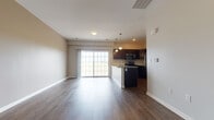 This single-floor residential unit offers a well-designed, open-concept layout that seamlessly connects the living area and kitchen. The living space features durable hardwood-style flooring and neutral-toned walls, creating a bright and inviting atmosphere. A large sliding glass door floods the area with natural light and provides access to an outdoor balcony with open views.

The kitchen is a standout feature, equipped with dark espresso cabinetry, granite countertops, and a full suite of stainless steel appliances including a refrigerator, microwave, and range. A peninsula island with a built-in sink and pendant lighting above serves as both a functional workspace and casual dining area.

The bedroom is generously proportioned, finished with plush carpeting and two windows that bring in ample natural light and outdoor views. Additional rooms include a hallway area with hardwood-style flooring and closet access, offering practical storage solutions.

The bathrooms are thoughtfully appointed, featuring dark vanity cabinetry, granite countertops, large mirrors, and hardwood-style flooring. One bathroom includes a walk-in shower, while another features a full soaking tub with a clean white surround. The overall aesthetic is cohesive, modern, and move-in ready.