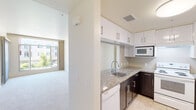This single-floor residence offers a clean, modern layout designed for comfortable everyday living. The kitchen is a functional centerpiece, featuring granite countertops, dark espresso lower cabinets paired with crisp white upper cabinets, tile flooring, a stainless steel sink, and a full suite of appliances including a refrigerator, electric range, microwave, and dishwasher. A breakfast bar with a granite overhang opens the kitchen toward the living area, which is finished with plush carpeting and elevated ceilings that contribute to a spacious, airy feel.

The bedrooms are carpeted and well-proportioned, with large windows that bring in natural light and views of the surrounding neighborhood. Each room offers ample wall space and closet access.

Two bathrooms serve the residence. The primary bathroom features a glass-enclosed walk-in shower with tile surround, a granite-topped vanity, and tile flooring. The secondary bathroom mirrors the design aesthetic with a dark wood vanity, granite countertop, and clean tile floors.

A dedicated in-unit laundry room provides added convenience, housing a full-size washer and dryer. Throughout the space, a neutral color palette, consistent finishes, and thoughtful layout create a bright, cohesive living environment.