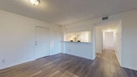 This well-designed single-floor residence offers a clean, neutral aesthetic throughout, with a thoughtful layout that maximizes both function and comfort. The main living area welcomes you with warm wood-look laminate flooring, crisp white walls, and a textured ceiling, creating a bright and open atmosphere. A pass-through window connects the living space directly to the kitchen, enhancing the open feel while maintaining defined zones. The kitchen is equipped with ample grey cabinetry, white appliances including an electric range and full-size refrigerator, a under-cabinet range hood, and a louvered pantry door for additional storage. Flooring here continues the wood-look laminate for a cohesive look. The bedrooms are carpeted for comfort and feature louvered bifold closet doors with built-in shelving and hanging rods. Large sliding glass doors fitted with vertical blinds allow natural light to fill the space and offer outdoor views. The bathrooms are finished with tile flooring and white tilework. One bathroom features a full tub-shower combination with a wide vanity and mirror, while a second bathroom provides a dedicated walk-in shower with floor-to-ceiling white tile. The overall palette is light and neutral, lending the space a clean, move-in-ready appeal.