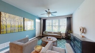 Located at 1715 Lake Michigan Dr in Valparaiso, Indiana, this single-floor residence offers a thoughtfully designed layout with a cohesive, contemporary aesthetic throughout. The living room makes a strong first impression with its bold teal accent wall, dark hardwood-style flooring, and a large picture window dressed with blinds and dark grommet curtains that invite generous natural light. A ceiling fan adds both comfort and style to the space, which flows naturally from the front entry. The kitchen is a functional and attractive centerpiece, featuring rich dark wood cabinetry, granite countertops, stainless steel appliances, and a large island with bar seating illuminated by pendant lighting — ideal for casual dining and entertaining. The bedroom is a serene retreat, with plush carpeting, a broad window overlooking the surrounding neighborhood, and a cool gray accent wall that lends a calm, restful atmosphere. The full bathroom is finished with granite vanity countertops, dark wood cabinetry, tile surround in the shower/tub combination, and hardwood-style flooring, balancing practicality with polished detail. Throughout the residence, consistent design choices — including coordinated color palettes and quality finishes — create a cohesive and inviting living environment.