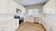 This well-appointed two-story home offers a thoughtfully designed layout with clean finishes and a neutral color palette that creates a bright, cohesive atmosphere throughout. The main level features an open-concept living area with light wood-tone laminate flooring, recessed lighting, and a staircase leading to the upper floor. The kitchen is a standout feature, outfitted with crisp white shaker-style cabinetry, a classic subway tile backsplash, light stone countertops, and a full suite of stainless steel appliances including a range, over-the-range microwave, dishwasher, and side-by-side refrigerator with ice and water dispenser. A window above the sink brings in natural light and overlooks the outdoors. Upstairs, the bedrooms are carpeted for comfort, featuring neutral walls and windows with blinds that offer views of the surrounding neighborhood. The bathrooms are finished in clean whites with full tub-shower combinations, vanities with mirrors, and tile-accented flooring. A dedicated laundry area houses a full-size top-loading washer and dryer. Throughout the home, consistent trim work, ample electrical outlets, and ceiling vents reflect a practical, move-in-ready design suited for comfortable everyday living.