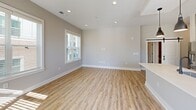 Located at 3426 Anson St in Charlotte, NC, this well-appointed 3-bedroom, 4-bathroom unit offers a thoughtfully designed single-floor layout with generous living space. The open-concept kitchen and living area features light wood-look flooring, recessed lighting, and large windows that flood the space with natural light. The kitchen is equipped with built-in stainless steel appliances, white countertops, gray cabinetry, and a stylish pendant light, with direct access to a private balcony overlooking the surrounding neighborhood and tree-lined streetscape. Each of the three bedrooms is carpeted and fitted with a ceiling fan, offering comfortable, quiet retreats with windows framing pleasant outdoor views. The primary bedroom includes its own dedicated bathroom. The bathrooms are finished with large-format marble-style tile, featuring a glass-enclosed shower, a soaking tub combination, and clean, modern fixtures throughout. Additional bathrooms maintain consistent design quality with tiled tub-shower combos and dark hardware accents. Each bedroom benefits from its own closet, and a central hallway connects the rooms with ease. The neutral color palette of warm grays and whites creates a cohesive, modern ambiance throughout the entire unit.