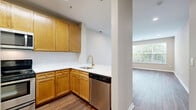 Located at 40 East Hanover Avenue in Morris Plains, NJ, this well-appointed one-bedroom, one-bathroom residence offers a thoughtfully designed single-floor layout. Rich wood-look flooring flows consistently throughout the entire space, lending warmth and visual continuity to every room.

The open-concept kitchen and living area serves as the heart of the home. The kitchen is outfitted with warm-toned maple cabinetry, gleaming white quartz countertops, a herringbone tile backsplash, and a gold-finish faucet. Stainless steel appliances — including a refrigerator, dishwasher, electric range, and over-the-range microwave — complete the space. A peninsula with additional counter space connects seamlessly to the dining and living areas, which are bathed in natural light from large windows.

The bedroom is a comfortable and well-proportioned retreat, featuring a large window with garden views, recessed lighting, and convenient access to both the full bathroom and a closet. The bathroom includes a full tub-shower combination with classic white tile and a decorative mosaic accent border. Additional storage is provided by two closets, and a dedicated laundry area adds everyday convenience. The living area features a sliding glass door that invites natural light and outdoor views.