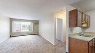 This single-floor residence at 6129 Beechfield Dr in Lansing, Michigan, offers a practical and well-organized layout designed for comfortable everyday living. The open living area is finished with neutral-toned carpet and features a wall-mounted air conditioning unit alongside baseboard heating, ensuring year-round climate control. A large window allows natural light to fill the space, creating a bright and welcoming atmosphere with outdoor views of the surrounding greenery.

The galley-style kitchen is efficiently arranged with warm wood-toned cabinetry lining both walls, offering generous storage above and below the laminate countertops. A stainless steel refrigerator, electric range, and a double-basin sink complete the kitchen's functional setup, while wood-look vinyl flooring adds a clean, durable finish.

The bedroom is a well-sized room with plush carpeting, a large window for natural light, and a spacious built-in closet equipped with shelving for organized storage. The transition between the bedroom's carpet and wood-look flooring in adjacent areas adds visual definition throughout the unit.

The bathroom features a full tub and shower combination with a white surround, a wood-toned vanity with countertop, and wood-look vinyl flooring, maintaining a cohesive and clean aesthetic throughout the space.