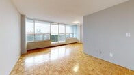 This 1-bedroom, 1-bathroom unit offers a thoughtfully organized layout that maximizes every square foot of its compact footprint. The living room is a standout space, anchored by expansive floor-to-ceiling windows that frame sweeping city skyline views and flood the room with natural light. Classic parquet hardwood flooring runs throughout the living, bedroom, and hallway areas, adding warmth and a timeless character to the interior.

The bedroom is a comfortable, well-proportioned space featuring its own window with city views, parquet flooring, and a pair of built-in closets that provide generous storage. The kitchen is designed in a galley configuration with modern grey cabinetry, granite-style countertops, a double stainless steel sink, and light tile flooring — offering both style and practicality.

The bathroom is clean and functional, featuring a tiled shower-tub combination, a granite-topped vanity with an under-mount sink, a medicine cabinet with mirror, and a coordinating grey tile floor. A connecting hallway links all rooms efficiently, contributing to the unit's logical and easy-to-navigate flow. Overall, the space presents a bright, functional, and well-maintained interior with notable views and classic design elements throughout.