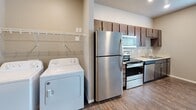 Located at 4550 49th Ave S in Fargo, North Dakota, this single-floor unit offers a practical and modern layout designed for comfortable everyday living. The kitchen is a standout feature, outfitted with rich dark-stained cabinetry, light countertops, and a full suite of stainless steel appliances including a refrigerator, electric range, built-in microwave, and dishwasher. Wood-style flooring runs throughout the main living areas, lending warmth and visual continuity to the space.

Adjacent to the kitchen, a dedicated in-unit laundry area provides added convenience, housing a full-size washer and dryer along with open shelving for storage. The open layout of the main living area offers flexibility for various furniture arrangements, with neutral-toned walls providing a clean, versatile backdrop.

The bathroom is finished with a full tub and shower combination featuring a bright white surround, chrome fixtures, and a grab bar, all set against the same consistent wood-style flooring. The bedroom is a well-proportioned, quiet space with neutral walls and ample room for furnishings. Throughout the unit, recessed and flush-mount lighting, clean white trim, and a cohesive neutral color palette create a tidy, move-in-ready environment.
