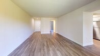 Located at 2930 Cherry St in Falls Church, VA, this single-floor, one-bedroom, two-bathroom unit offers a well-organized layout designed to maximize comfort and functionality. The living areas feature light-toned hardwood-style flooring throughout, complemented by neutral warm beige walls that create a bright, clean atmosphere. The main living room is a generous space anchored by a floor-to-ceiling sliding glass door that floods the room with natural light and provides direct views of lush outdoor greenery. A second living area offers additional flexible space for dining or a home office. The kitchen is thoughtfully equipped with white shaker cabinetry, a stainless steel dishwasher, a gas range with microwave, and a stacked in-unit washer and dryer — a practical convenience. Light wood-style flooring in the kitchen provides a seamless transition from the living spaces. The spacious primary bedroom features a vertical-blind window allowing for adjustable natural light. Two bathrooms serve the unit: one features a wide vanity with ample counter space and mirror, while the second includes a full tub-shower combination with tile surround. Two closets and a hallway provide additional storage throughout. The overall ambiance is clean, modern, and move-in ready.