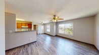 This single-story residence offers a practical and comfortable layout designed for everyday living. The open-concept living and dining area is bright and welcoming, featuring durable wood-look flooring, neutral gray walls, and a ceiling fan overhead. Large windows on multiple walls invite abundant natural light and provide views of the surrounding greenery, enhancing the sense of openness. A breakfast bar seamlessly connects the living space to the galley-style kitchen, which is outfitted with warm wood cabinetry, light countertops, a stainless steel sink, a gas range, a dishwasher, and a full-size refrigerator. The kitchen also includes a dedicated pantry or utility closet for added storage. The two bedrooms are carpeted for comfort and each features a ceiling fan and closet storage — one bedroom includes a spacious walk-in closet, while the other offers a standard sliding-door closet. Both bathrooms include wood-look flooring, vanities with light countertops, and shower-tub combinations. The layout flows efficiently throughout, making this a well-appointed single-floor home suited for a range of occupants.