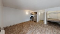 Located at 1521 Hickory Valley Rd in Chattanooga, Tennessee, this single-floor unit offers a thoughtfully arranged layout that makes efficient use of its cozy footprint. The living area is bright and open, featuring wood-look laminate flooring and clean white walls that lend a fresh, neutral aesthetic throughout. A textured ceiling adds subtle architectural character to the space. Large sliding glass doors allow abundant natural light to pour in and provide direct access to a private balcony, offering pleasant outdoor views and a seamless indoor-outdoor connection. A wall-mounted air conditioning unit ensures year-round comfort. The kitchen is tucked efficiently at one end of the main living space and is equipped with stainless steel appliances, including a gas range, microwave, and refrigerator, complemented by warm wood-toned cabinetry. The bathroom features a clean, all-white tub and shower combination with chrome fixtures, maintaining the unit's consistent, crisp aesthetic. The overall layout flows logically from the living and kitchen areas toward the bathroom, making practical use of every square foot. The light color palette and natural light from the balcony-facing windows create a welcoming and airy atmosphere throughout the unit.