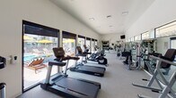 Located at 3470 Lee Cir in Prescott, Arizona, this well-appointed fitness center offers a comprehensive workout environment designed to accommodate a wide range of exercise routines. The single-floor space is generously sized, with vaulted ceilings that contribute to an open, airy atmosphere throughout.

The cardio zone is equipped with multiple treadmills, elliptical trainers, and stationary bikes from Life Fitness, all positioned along a wall of large, floor-to-ceiling windows. These expansive windows flood the space with natural light and provide direct views of the outdoor pool deck, complete with lounge chairs and vibrant yellow umbrellas, creating an energizing backdrop for workouts.

The strength training area features a multi-station cable machine, a dedicated TRX Training Zone with suspension straps and weighted accessories, a rack of dumbbells, and wall-mounted mirrors that enhance the sense of space. Posted fitness guidelines and safety equipment, including an AED, reflect a commitment to user safety.

The flooring throughout is durable, cushioned gym-grade material, ideal for both cardio and strength activities. The space is well-lit with recessed lighting, climate-controlled, and includes a mounted television for entertainment. Direct access to the outdoor pool and patio area makes this fitness center a seamlessly integrated part of the broader amenity offering.