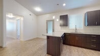 This single-floor residence offers a thoughtfully designed open layout with a clean, contemporary aesthetic throughout. The kitchen serves as a central highlight, showcasing dark espresso cabinetry paired with granite countertops, a white subway tile backsplash, and stainless steel appliances including a gas range, microwave, and refrigerator. A peninsula island provides additional prep space and casual seating, while pendant lighting and recessed fixtures illuminate the area. Light wood-style flooring flows through the kitchen and living areas, lending warmth and continuity to the space.

Two carpeted bedrooms offer a comfortable, quiet retreat, with at least one featuring a window fitted with blinds for natural light and privacy. The unit includes two full bathrooms, each finished with wood-look flooring, a tub-shower combination, and a vanity with a granite countertop and dark cabinetry consistent with the kitchen's design. A dedicated laundry area accommodates a full-sized side-by-side washer and dryer with overhead shelving for added storage. The overall ambiance is modern and move-in ready, with neutral tones and consistent finishes creating a cohesive, functional living environment.