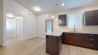 This single-floor residence offers a thoughtfully designed open layout with a clean, contemporary aesthetic throughout. The kitchen serves as a central highlight, showcasing dark espresso cabinetry paired with granite countertops, a white subway tile backsplash, and stainless steel appliances including a gas range, microwave, and refrigerator. A peninsula island provides additional prep space and casual seating, while pendant lighting and recessed fixtures illuminate the area. Light wood-style flooring flows through the kitchen and living areas, lending warmth and continuity to the space.

Two carpeted bedrooms offer a comfortable, quiet retreat, with at least one featuring a window fitted with blinds for natural light and privacy. The unit includes two full bathrooms, each finished with wood-look flooring, a tub-shower combination, and a vanity with a granite countertop and dark cabinetry consistent with the kitchen's design. A dedicated laundry area accommodates a full-sized side-by-side washer and dryer with overhead shelving for added storage. The overall ambiance is modern and move-in ready, with neutral tones and consistent finishes creating a cohesive, functional living environment.