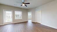 This single-story residence offers a thoughtfully designed layout across two bedrooms, two bathrooms, and a combined kitchen and living area, making efficient use of its comfortable footprint. Throughout the main living spaces, warm hardwood-style flooring creates a cohesive and inviting atmosphere, complemented by neutral beige walls and crisp white trim.

The open living area features ceiling fans with integrated lighting and multiple windows fitted with blinds, allowing for ample natural light and outdoor views. A glass door in the living space provides additional light and exterior access. The kitchen is well-equipped with dark espresso cabinetry, white quartz countertops, stainless steel appliances including a gas range, dishwasher, and refrigerator, plus pendant lighting over the sink island.

The primary bedroom includes a ceiling fan and its own en-suite bathroom, which features a dual-sink vanity with dark cabinetry, a glass-enclosed walk-in shower, and elegant marble-style tile flooring. The second bathroom offers a tub-shower combination, matching cabinetry, and the same marble-style tile. Both bedrooms include closets and natural light from exterior windows. A dedicated laundry room accommodates a full-size washer and dryer.