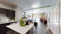 This single-floor residence offers a thoughtfully designed open-concept layout that seamlessly connects the kitchen, dining, and living areas. The kitchen is a standout feature, equipped with dark espresso cabinetry, stainless steel appliances including a refrigerator, range, and microwave, and clean white quartz countertops that extend to a peninsula with bar seating. Wood-style flooring runs throughout the main living area, adding warmth and continuity to the space.

The living room is bright and welcoming, benefiting from generous natural light that filters through a large sliding glass door with vertical blinds, offering access to an outdoor area. The open dining space flows naturally between the kitchen and living room, making the layout well-suited for both everyday living and entertaining.

The bedroom provides a comfortable retreat, featuring plush carpet flooring, a large window dressed with ombre curtains that allow for ample natural light, and neutral wall tones that create a calm atmosphere. The full bathroom is finished with wood-look tile flooring, dark vanity cabinetry with white countertops, and a shower-tub combination. Throughout the unit, consistent finishes and a cohesive modern design aesthetic tie each space together seamlessly.