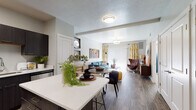 This single-floor residence offers a thoughtfully designed open-concept layout that seamlessly connects the kitchen, dining, and living areas. The kitchen is a standout feature, equipped with dark espresso cabinetry, stainless steel appliances including a refrigerator, range, and microwave, and clean white quartz countertops that extend to a peninsula with bar seating. Wood-style flooring runs throughout the main living area, adding warmth and continuity to the space.

The living room is bright and welcoming, benefiting from generous natural light that filters through a large sliding glass door with vertical blinds, offering access to an outdoor area. The open dining space flows naturally between the kitchen and living room, making the layout well-suited for both everyday living and entertaining.

The bedroom provides a comfortable retreat, featuring plush carpet flooring, a large window dressed with ombre curtains that allow for ample natural light, and neutral wall tones that create a calm atmosphere. The full bathroom is finished with wood-look tile flooring, dark vanity cabinetry with white countertops, and a shower-tub combination. Throughout the unit, consistent finishes and a cohesive modern design aesthetic tie each space together seamlessly.