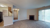 This well-appointed 2-bedroom, 2-bathroom single-floor residence offers a functional and comfortable layout with consistent neutral tones and warm finishes throughout. The open living area serves as the heart of the home, featuring plush carpeting, a classic brick fireplace, and sliding door access to the exterior. A breakfast bar connects the living space to the galley-style kitchen, which is equipped with black appliances, ample oak cabinetry, light stone countertops, and durable hardwood-style flooring — providing both practicality and warmth. A dedicated laundry area is conveniently accessible directly from the kitchen. Both bedrooms are generously sized, carpeted, and filled with natural light from large windows that offer leafy outdoor views. Each bedroom provides easy access to its own bathroom. The two bathrooms feature oak vanity cabinetry, stone-tone countertops, tub-shower combinations, and tile flooring. One bathroom includes a large wall mirror with overhead vanity lighting, adding brightness to the space. Clean white walls, consistent trim work, and well-distributed closet storage round out this thoughtfully designed residence.