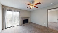 This single-story, 1-bedroom, 1-bathroom unit offers a functional and comfortable layout across a well-designed floor plan. The living room serves as the heart of the home, featuring plush carpeting, a textured ceiling, a ceiling fan with integrated lighting, and a standout brick fireplace with a raised hearth — an ideal focal point for the space. A sliding glass door with vertical blinds allows natural light to pour in while providing access to the outdoors.

The open-concept transition between the living area and kitchen is facilitated by a breakfast bar with light countertops, creating a connected and practical flow. The galley-style kitchen is efficiently arranged with wood-look flooring, gray cabinetry, light stone countertops, and a full suite of black appliances including a refrigerator, electric range, built-in microwave, and dishwasher. A separate pantry or storage closet is accessible directly from the kitchen.

The bedroom is comfortably sized, featuring carpeted flooring, a ceiling fan with a light kit, and a window with blinds that brings in natural light. The bathroom includes a wide vanity with light countertops, ample cabinet storage, a large mirror, and a separate tub-shower combination. Wood-look flooring extends through the bathroom, adding a cohesive finish throughout the unit.