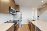 Located at 3533 Moncure Ave in Falls Church, VA, this contemporary three-bedroom, three-bathroom townhouse is thoughtfully designed across three floors. The ground level features a garage and utility space, providing convenient entry and storage. The main living floor serves as the heart of the home, showcasing an open-concept layout that seamlessly connects the kitchen, dining, and living areas. The modern kitchen is outfitted with stainless steel appliances including a refrigerator, range, microwave, and dishwasher, complemented by sleek two-tone cabinetry, white quartz countertops, a central island with sink, and a subway tile backsplash. Light hardwood flooring flows throughout, enhancing the bright, airy atmosphere created by generous windows. A balcony extends the living space outdoors. The upper floor houses the bedrooms, each featuring light hardwood floors, neutral tones, and natural light from well-placed windows with blinds. Bedrooms include closets, and the bathrooms feature clean, modern finishes with subway tile surrounds and contemporary vanities. A dedicated laundry area and four closets add practical functionality. The clean white walls, recessed lighting, and modern hardware throughout lend the home a cohesive, refined aesthetic.