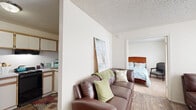 This well-organized one-bedroom, one-bathroom unit offers a thoughtfully arranged single-floor layout that maximizes every square foot. The living room serves as the central gathering space, featuring wood-style plank flooring, large windows with sheer curtains and blinds that allow abundant natural light to fill the room, and a textured ceiling. The open sightline from the living area to the bedroom creates a sense of continuity throughout the unit.

The kitchen is efficiently laid out with light wood cabinetry, black appliances including a gas range and refrigerator, and a clean, functional workspace. The wood-style flooring carries through this area, maintaining a cohesive aesthetic.

The bedroom is a cozy, carpeted retreat with a window providing natural light and wall-unit climate control. A dedicated closet with built-in shelving and a hanging rod offers practical storage solutions.

The bathroom features a full tub and shower combination with classic white tile surround, maintaining a clean and straightforward design. Neutral wall tones and a textured ceiling are consistent throughout the unit, contributing to a bright and airy overall ambiance suited for comfortable, low-maintenance living.