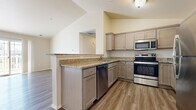 This single-floor residence is designed with a practical and contemporary layout, offering a variety of well-finished living spaces. The kitchen serves as a functional centerpiece, featuring granite countertops, taupe cabinetry, and a full suite of stainless steel appliances including a range, microwave, dishwasher, and refrigerator. A peninsula with bar-height countertop extends into the adjacent living area, creating a natural transition between spaces.

The living area is highlighted by vaulted ceilings and a ceiling fan, contributing to an open and airy atmosphere. Durable hardwood-style plank flooring runs throughout the main living and kitchen areas, while carpeting provides comfort in the bedrooms. A sliding glass door opens to a private patio, allowing natural light to fill the space and providing views of the surrounding neighborhood.

The bedrooms are spacious and neutrally finished, with windows that bring in additional natural light and outdoor views. The bathroom includes a walk-in shower with a clean, white surround and wood-style flooring. A dedicated utility area accommodates the HVAC system and in-unit laundry, adding to the overall convenience of this well-organized residence.