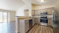 This single-floor residence is designed with a practical and contemporary layout, offering a variety of well-finished living spaces. The kitchen serves as a functional centerpiece, featuring granite countertops, taupe cabinetry, and a full suite of stainless steel appliances including a range, microwave, dishwasher, and refrigerator. A peninsula with bar-height countertop extends into the adjacent living area, creating a natural transition between spaces.

The living area is highlighted by vaulted ceilings and a ceiling fan, contributing to an open and airy atmosphere. Durable hardwood-style plank flooring runs throughout the main living and kitchen areas, while carpeting provides comfort in the bedrooms. A sliding glass door opens to a private patio, allowing natural light to fill the space and providing views of the surrounding neighborhood.

The bedrooms are spacious and neutrally finished, with windows that bring in additional natural light and outdoor views. The bathroom includes a walk-in shower with a clean, white surround and wood-style flooring. A dedicated utility area accommodates the HVAC system and in-unit laundry, adding to the overall convenience of this well-organized residence.