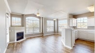 This single-story home is thoughtfully designed with an open layout and a neutral color palette of warm taupe and crisp white throughout. The living area serves as the heart of the home, showcasing vaulted ceilings, a ceiling fan, and a corner fireplace framed by large windows that flood the space with natural light and offer views of the surrounding neighborhood. Wood-look flooring extends through the living area and into the kitchen, creating a cohesive flow.

The kitchen features white cabinetry, light stone-look countertops, a peninsula with additional seating space, a double sink, and white appliances, including a refrigerator and dishwasher. Multiple windows keep the kitchen bright and airy.

A hallway connects the living spaces to the private areas of the home. The bedrooms are carpeted and spacious, each equipped with ceiling fans and vaulted ceilings that enhance the sense of openness. One bedroom includes built-in shelving and sliding glass door access to an outdoor area.

The bathrooms feature wood-look tile flooring, white vanity cabinetry, and well-lit mirrors. A dedicated hallway with panel doors provides practical entry-level storage. Overall, the home offers a clean, comfortable, and functional living environment.
