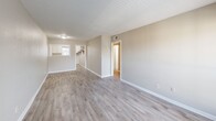 Located at 1561 Pike Road in Birmingham, Alabama, this single-floor, 2-bedroom, 2-bathroom home offers a practical and well-organized layout. The open-plan living and dining area serves as the heart of the home, featuring light gray luxury vinyl plank flooring, neutral beige walls, a textured ceiling, and a large sliding glass door that floods the space with natural light and provides an outdoor view. The kitchen is positioned adjacent to the living area and features white cabinetry, offering a clean and functional workspace. A hallway connects the main living areas to the private quarters, which include three closets and a dedicated utility room for added convenience. Both bedrooms are carpeted in a warm neutral tone and are equipped with windows that allow natural light to enter. The primary bedroom is generously sized and includes a closet. The two bathrooms differ in style: one features wood-look vinyl flooring with a full tub-shower surround, while the second showcases classic white tile wainscoting. Throughout the home, clean white baseboards and neutral wall tones create a cohesive, move-in-ready aesthetic suited for comfortable everyday living.