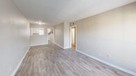 Located at 1561 Pike Road in Birmingham, Alabama, this single-floor, 2-bedroom, 2-bathroom home offers a practical and well-organized layout. The open-plan living and dining area serves as the heart of the home, featuring light gray luxury vinyl plank flooring, neutral beige walls, a textured ceiling, and a large sliding glass door that floods the space with natural light and provides an outdoor view. The kitchen is positioned adjacent to the living area and features white cabinetry, offering a clean and functional workspace. A hallway connects the main living areas to the private quarters, which include three closets and a dedicated utility room for added convenience. Both bedrooms are carpeted in a warm neutral tone and are equipped with windows that allow natural light to enter. The primary bedroom is generously sized and includes a closet. The two bathrooms differ in style: one features wood-look vinyl flooring with a full tub-shower surround, while the second showcases classic white tile wainscoting. Throughout the home, clean white baseboards and neutral wall tones create a cohesive, move-in-ready aesthetic suited for comfortable everyday living.