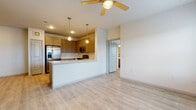 This single-floor residence offers a clean, modern design with light wood-style flooring and neutral tones carried consistently throughout the space. The open-concept layout connects the living area to a well-equipped kitchen, which features warm-toned cabinetry, a suite of stainless steel appliances including a French door refrigerator, range, microwave, and dishwasher, as well as a peninsula with a built-in sink and pendant lighting overhead. A ceiling fan in the living area adds both function and style to the space.

The bedrooms are generously proportioned, each featuring ceiling fans, light-filled windows with blinds, and access to closet space. The rooms maintain the same light flooring and neutral palette, creating a cohesive and airy atmosphere.

Two bathrooms serve the residence. One features a soaking tub with tiled surround, a vanity with taupe cabinetry, and a white countertop. The other offers a single vanity with matching cabinetry, a framed mirror, and overhead lighting. Both bathrooms continue the light flooring found throughout the home.

A dedicated laundry area with side-by-side washer and dryer is also visible, adding everyday convenience. Overall, the space presents a bright, functional, and well-designed living environment.