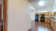 Located at 4643 36th Ave S in Fargo, North Dakota, this 1-bedroom, 1-bathroom unit offers a functional and comfortable single-floor layout. The kitchen is a standout feature, boasting light maple cabinetry extending to near the ceiling, stone-look countertops, and black appliances including a refrigerator, range, microwave, and dishwasher. High ceilings and a transom window above the kitchen flood the space with natural light, while warm-toned hardwood-style flooring ties the kitchen and adjacent living area together seamlessly. The living area transitions to plush carpeting, creating a cozy atmosphere. The bedroom is a comfortable size, featuring carpet flooring, a baseboard heater, and a window with exterior views, offering natural light and an outdoor connection. An adjacent walk-in closet provides generous storage with wire shelving systems on multiple walls. The full bathroom is well-equipped with a wide vanity, wood cabinetry, a large mirror with overhead lighting, tile flooring, and a full tub-shower combination. A dedicated laundry room includes a full-size washer and dryer with overhead wire shelving for added storage convenience. A hallway connects all areas efficiently, completing this practical and thoughtfully designed living space.