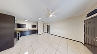 This single-story home offers a practical and cohesive layout across three bedrooms, two bathrooms, a dedicated kitchen, a hallway, and three closets. The open living area greets you upon entry through a bold dark front door, featuring large-format polished white tile flooring, neutral cream walls with dark baseboards, and a ceiling fan with integrated lighting — a combination that keeps the space feeling bright and airy. Natural light filters in through horizontal-pane windows, adding warmth to the open layout.

The kitchen is well-appointed with dark espresso cabinetry, granite-style countertops, stainless steel appliances including a range and refrigerator, and a double sink — offering both functionality and style. The cabinetry continues to the upper walls, providing ample storage.

Each bedroom continues the tile flooring and ceiling fan theme, maintaining a consistent, clean aesthetic throughout. The spacious primary bedroom features vaulted ceilings and its own closet. Secondary bedrooms are comfortably sized with natural window light.

Both bathrooms are finished with large-format warm beige wall tiles, decorative mosaic accent borders, walk-in showers with raised tile bases, dark wall-mounted cabinetry, and white fixtures — delivering a clean, modern feel. The consistent design language across the entire home creates a unified and well-maintained living environment.