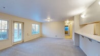 This single-floor, 3-bedroom, 2-bathroom residence offers a functional and comfortable layout designed to maximize everyday living. The open-concept living room is a standout feature, with soft carpet flooring, neutral warm-toned walls, and multiple windows fitted with blinds that allow ample natural light to fill the space. A sliding glass door provides direct outdoor access, adding to the bright and airy feel of the main living area.

The kitchen is thoughtfully designed with white cabinetry, granite-style countertops, and stainless steel appliances including a refrigerator, range, and built-in microwave. A peninsula with bar seating creates a seamless transition between the kitchen and living space, ideal for casual dining or entertaining. Adjacent to the kitchen, an in-unit laundry area adds everyday convenience.

Each of the three bedrooms features plush carpet flooring, neutral walls, and generous closet space with built-in shelving and hanging rods. The primary bedroom is well-sized and includes its own dedicated closet. A connecting hallway links the bedrooms to both bathrooms, each finished with wood-look tile flooring, white vanity cabinetry, granite-style countertops, and a full shower-tub combination. The overall ambiance throughout the home is clean, bright, and move-in ready.