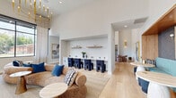 Located in the heart of Nashville's vibrant East Side at 401 S Fourth St, this thoughtfully designed single-floor community lounge offers an impressive blend of modern aesthetics and functional versatility across a generous footprint. Soaring ceilings define the dramatic scale of the space, amplifying the sense of openness throughout.

The living area is anchored by a wood-clad fireplace flanked by built-in shelving, with a wall-mounted television above a warm wood mantle. Multiple seating arrangements cater to both social gatherings and quiet retreat, including a marble-top table surrounded by curved blush chairs and a tufted banquette nook upholstered in bold teal, set within a warm wood surround with navy patterned wallcovering.

Floor-to-ceiling black-framed windows line the exterior wall, flooding the space with natural light and offering open views of the surrounding neighborhood. Light hardwood flooring runs throughout, complementing the crisp white walls and lending warmth to the overall palette.

The kitchen area is a design standout, featuring deep navy vertical tile extending from countertop to ceiling, white cabinetry with matte black hardware, open wood floating shelves, stainless steel appliances, and woven pendant lighting overhead. Together, these elements create a cohesive, design-forward space well-suited for community use.