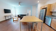 Located at 1201 Third Ave S in Birmingham, Alabama, this 2-bedroom unit offers a clean, modern layout designed for comfortable everyday living. The open-concept living and dining area serves as the heart of the space, featuring warm hardwood-style flooring, bright white walls, and natural light streaming through multiple windows. A ceiling fan overhead adds to the comfort of the living area, which is furnished with a large sectional sofa, wall-mounted television, and a high-top dining table with bar stools — ideal for both relaxing and casual dining.

The kitchen is well-appointed with light maple cabinetry, granite-style countertops, and a full suite of stainless steel appliances including a refrigerator, electric range, microwave, and dishwasher. The space flows seamlessly between the kitchen and living areas, creating an open and connected feel.

Each bedroom is thoughtfully laid out with carpeted flooring, a bed frame with built-in storage, a dedicated desk and chair, and a window allowing natural light. The bathrooms feature hardwood-style tile flooring, maple vanity cabinetry with granite countertops, and a tub-shower combination. Additional storage is provided through walk-in closet space adjacent to the bathroom, rounding out this practical and well-designed residential unit.